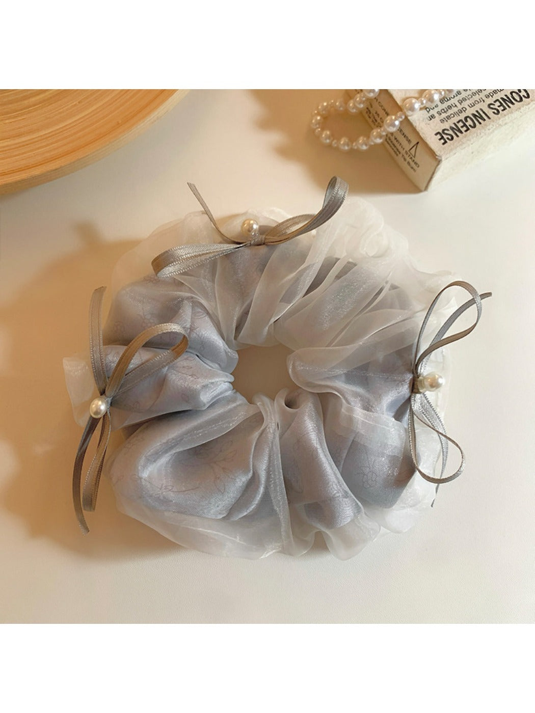 Close-up of Gifty tulle ribbon bow scrunchie in soft pink on white background
