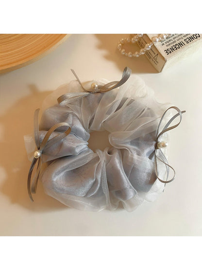 Close-up of Gifty tulle ribbon bow scrunchie in soft pink on white background