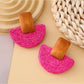 Earedge raffia mushroom shaped stud earrings worn on a model's ear