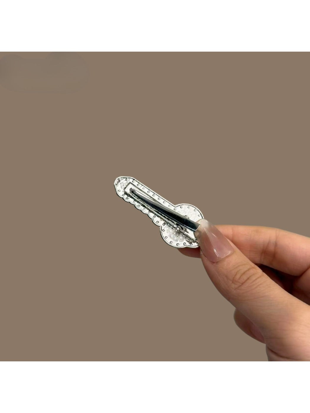 Beau key shaped hair clip holding back brown hair in a half-up hairstyle