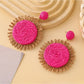Top view of round raffia earrings highlighting intricate weaving