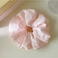 Side view of Gifty checkered scrunchie displaying its gathered fabric and elastic band