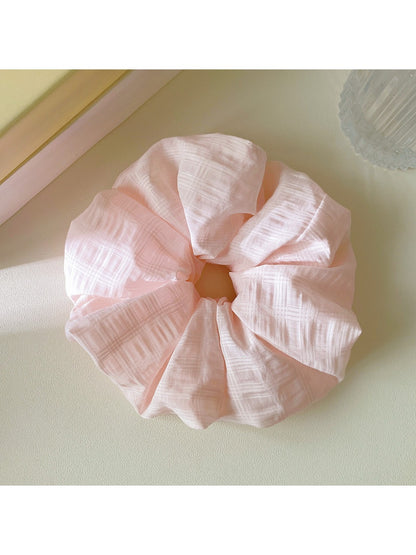 Side view of Gifty checkered scrunchie displaying its gathered fabric and elastic band