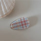 Beau hair clip resting on a fabric background, highlighting its gold tone and texture