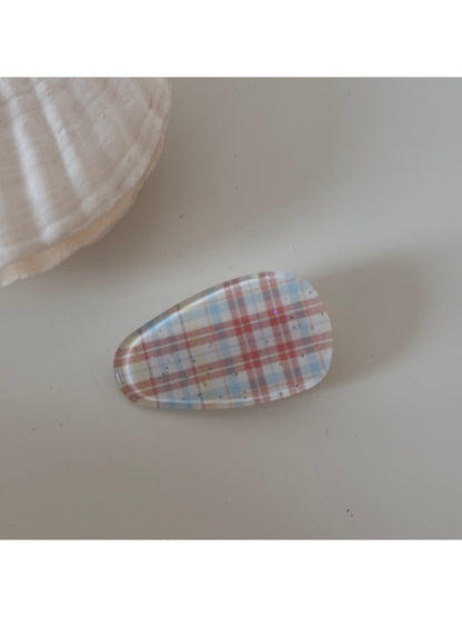 Beau hair clip resting on a fabric background, highlighting its gold tone and texture