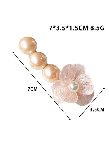 Beau Camellia beaded hair clip held in hand displaying size and shape