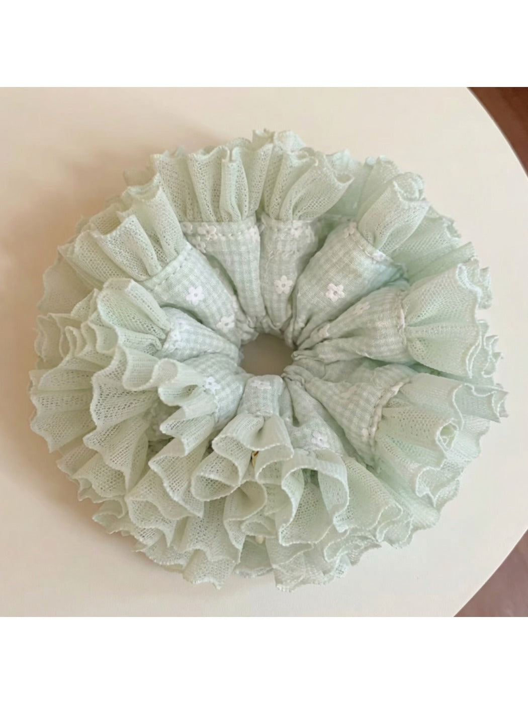 Mint green plaid tulle ruffle scrunchie styled on a wrist as an accessory