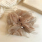 Gifty scrunchie styled on a wrist showing its bow detail and smooth texture