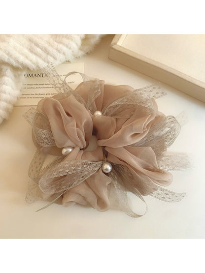 Gifty scrunchie styled on a wrist showing its bow detail and smooth texture