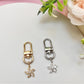 Close-up of Keypus flower-shaped charm keychain with gold finish on white background