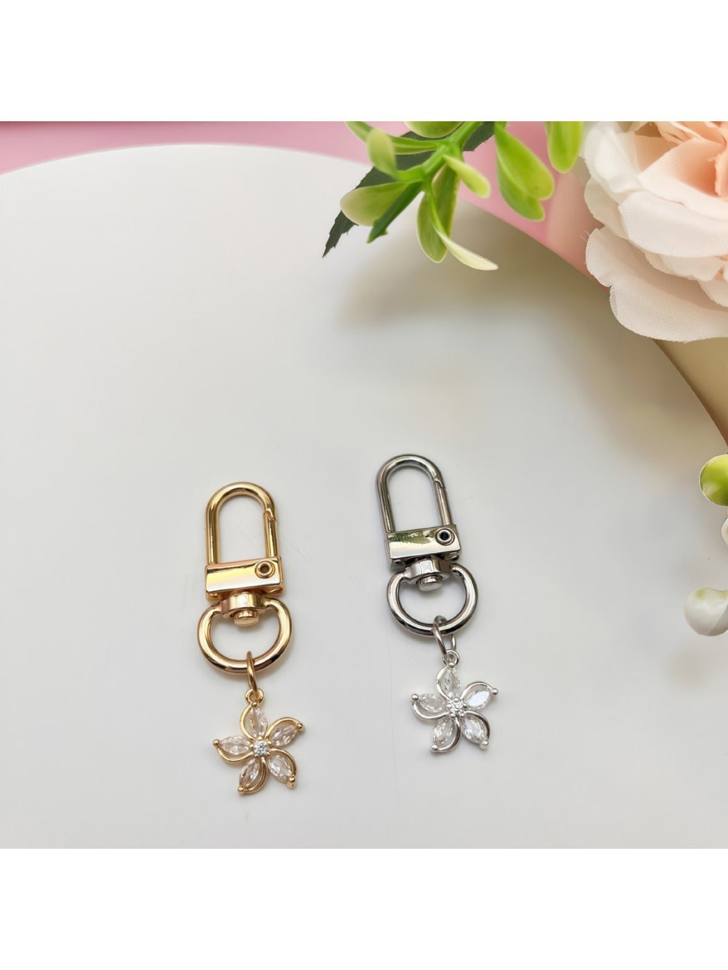 Close-up of Keypus flower-shaped charm keychain with gold finish on white background
