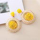 Earedge raffia earrings styled with casual outfit on a wooden surface