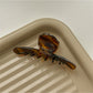 Beau brown acetate claw clip placed on wooden surface with natural light