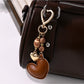 Brown heart-shaped leather keychain with metal ring on white background