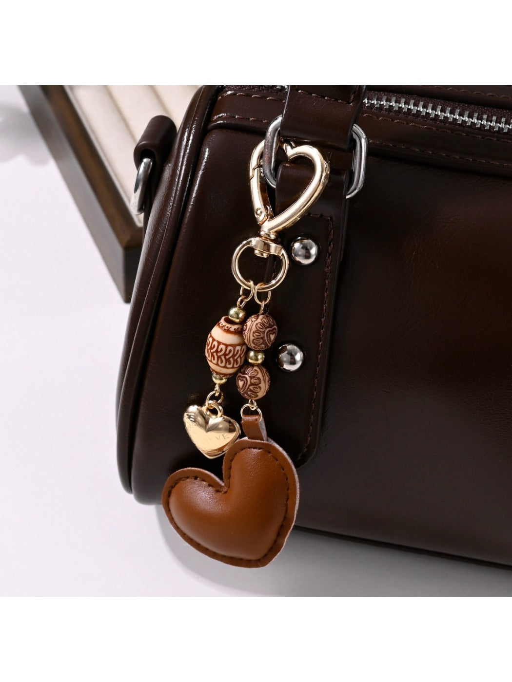 Brown heart-shaped leather keychain with metal ring on white background