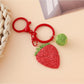 Strawberry charm keychain attached to a set of keys on a wooden surface