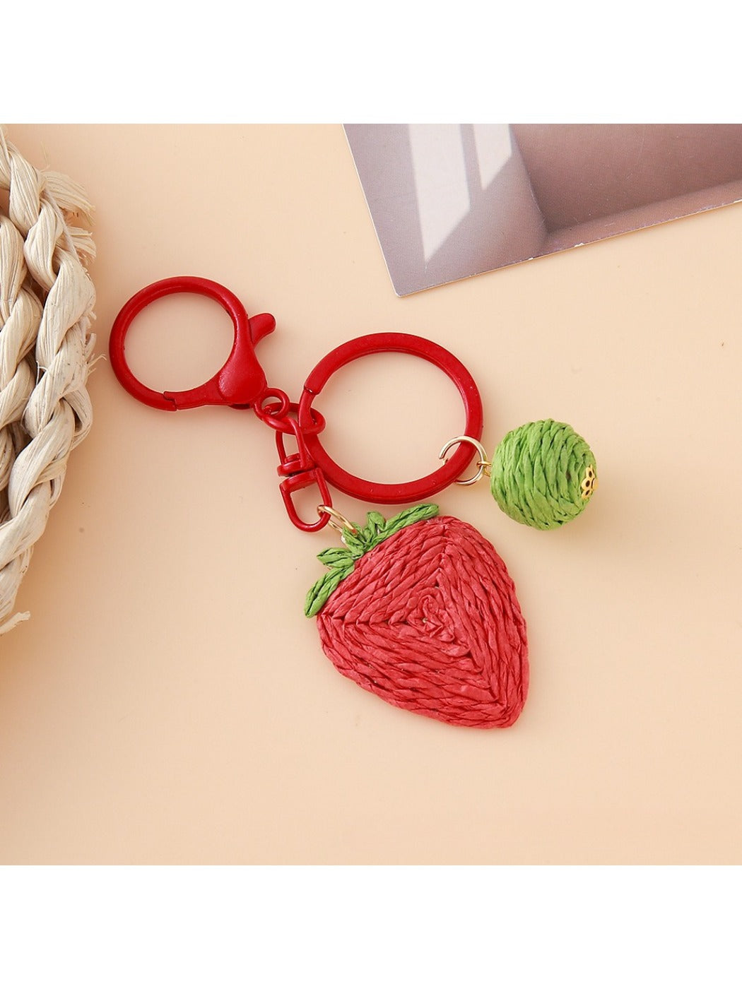 Strawberry charm keychain attached to a set of keys on a wooden surface