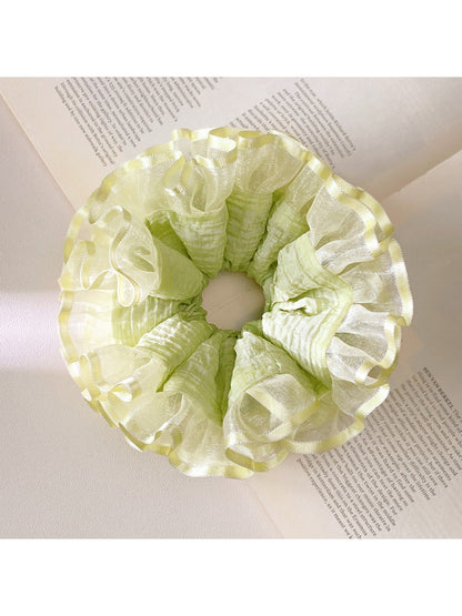 Close-up of light green ruffle scrunchie showing texture and fabric folds