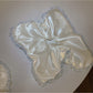 Satin white lace trim scrunchie packaged in a clear plastic bag with branding