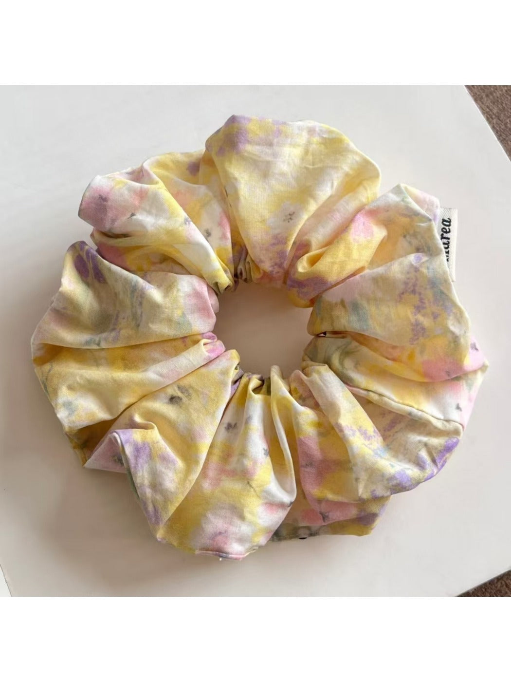 Hand holding a colorful scrunchie featuring artistic oil painting inspired print