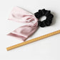 Satin bow hair tie displayed flat with visible elastic band in matching color