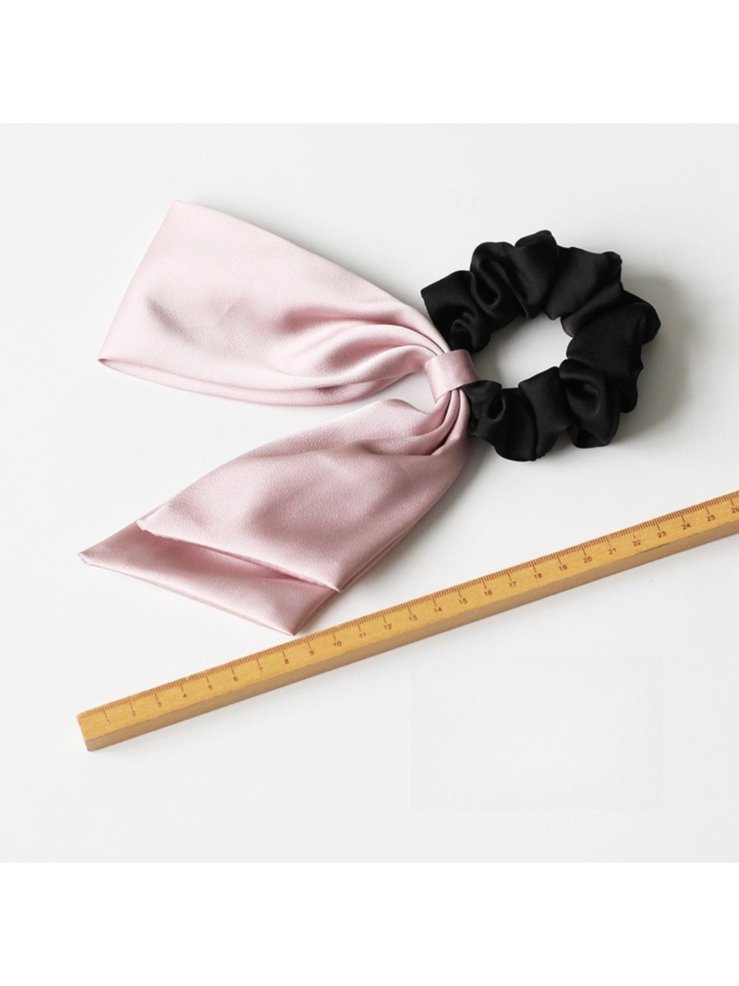 Satin bow hair tie displayed flat with visible elastic band in matching color
