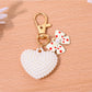Heart shaped bag charm keychain with gold hardware hanging from a purse strap