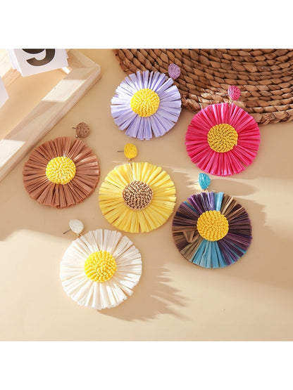 Close-up of a single raffia sunflower-shaped earring with yellow petals and a brown center