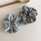 Striped fabric scrunchie with muted vintage colors displayed flat on a wooden surface