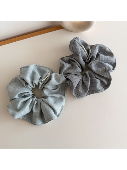 Striped fabric scrunchie with muted vintage colors displayed flat on a wooden surface