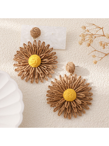 Pair of colorful floral raffia statement earrings on a neutral fabric background