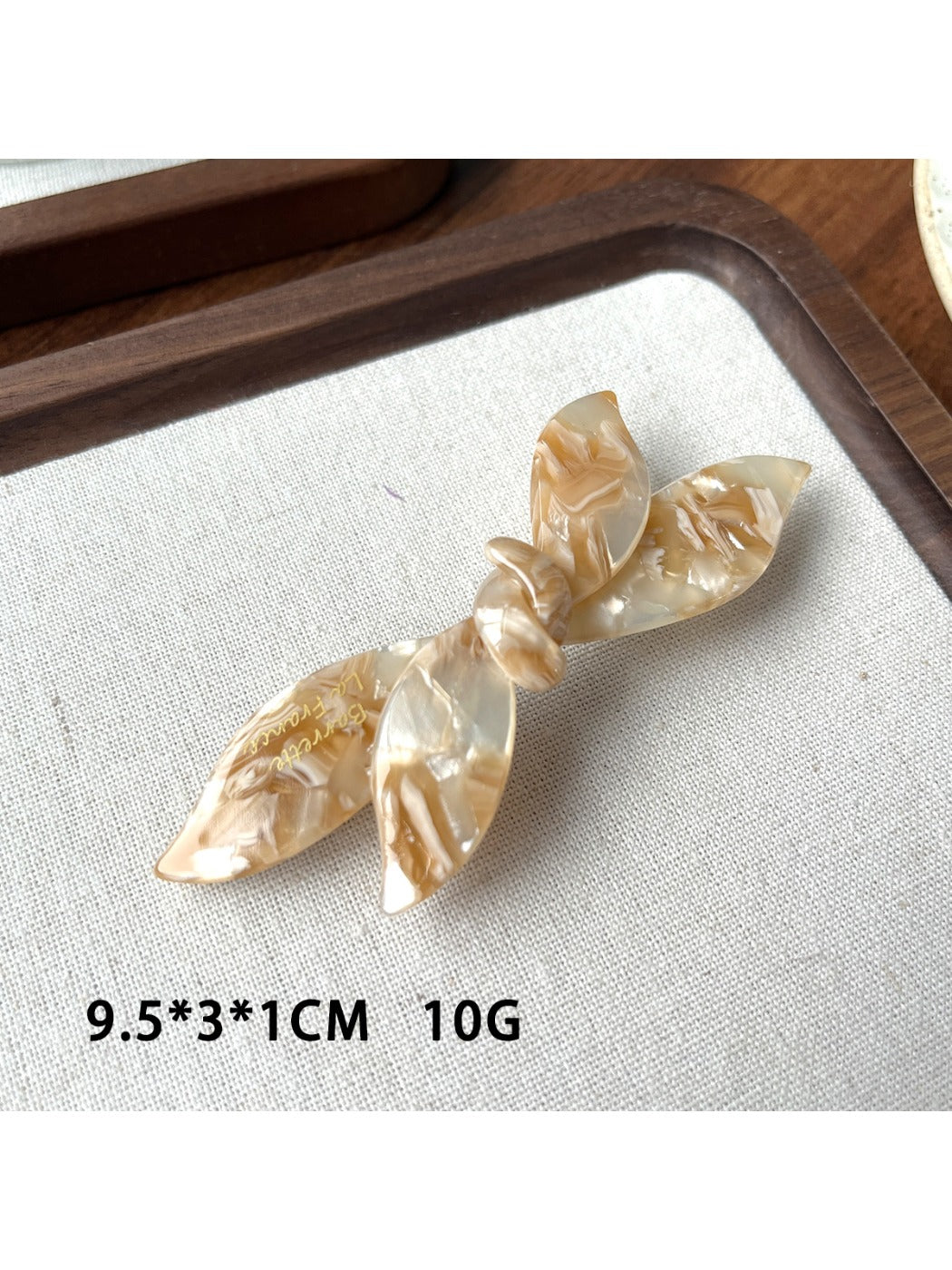 Beau bow shaped updo hair clip in beige shown with other hair accessories