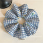 Close-up of embroidered white flower on blue plaid scrunchie fabric