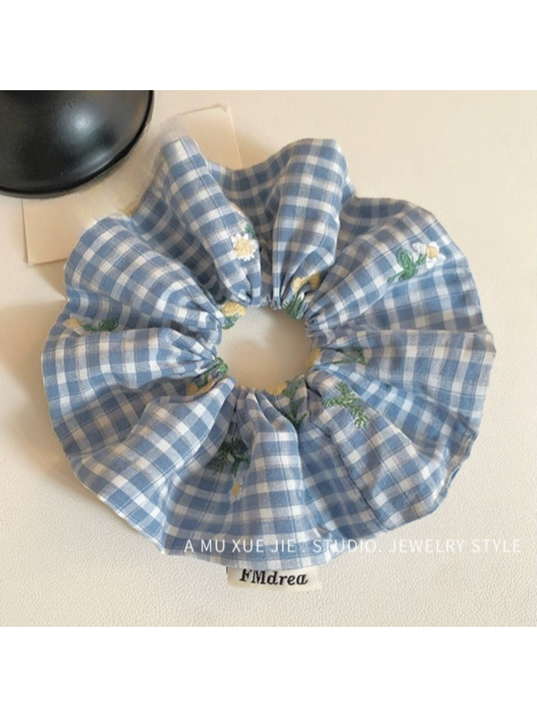 Close-up of embroidered white flower on blue plaid scrunchie fabric