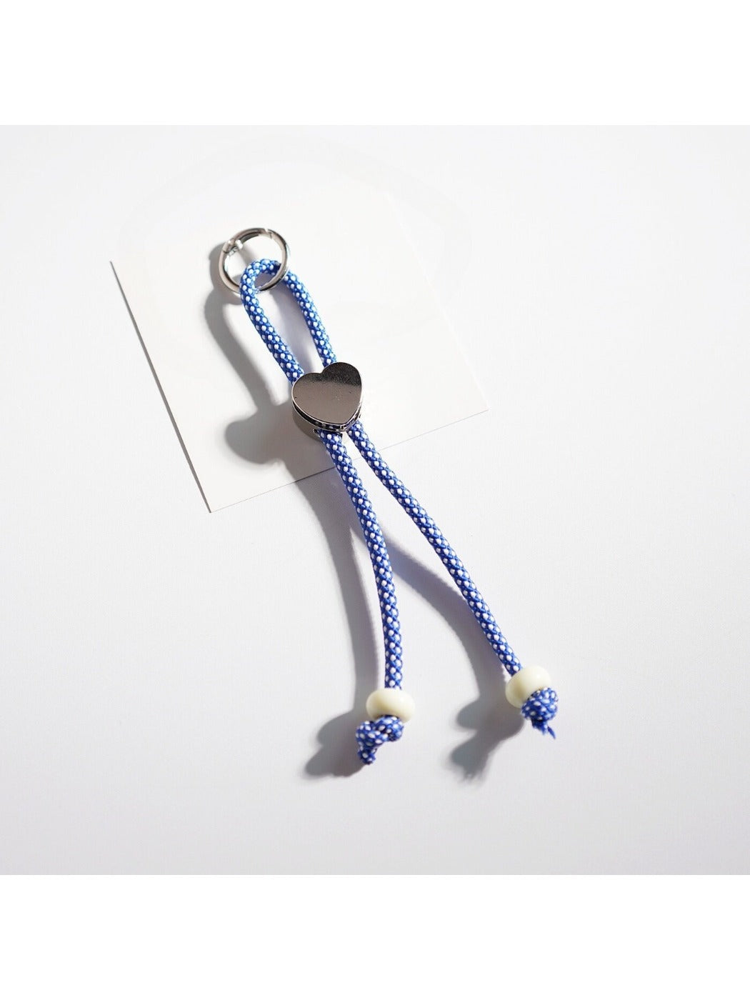 Keychain heart made of multicolored ropes with a metal ring on a wooden surface