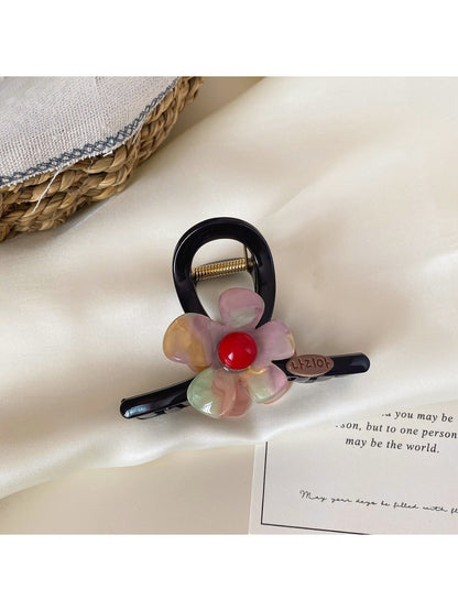 Beau flower claw clip resting on white surface with soft shadows
