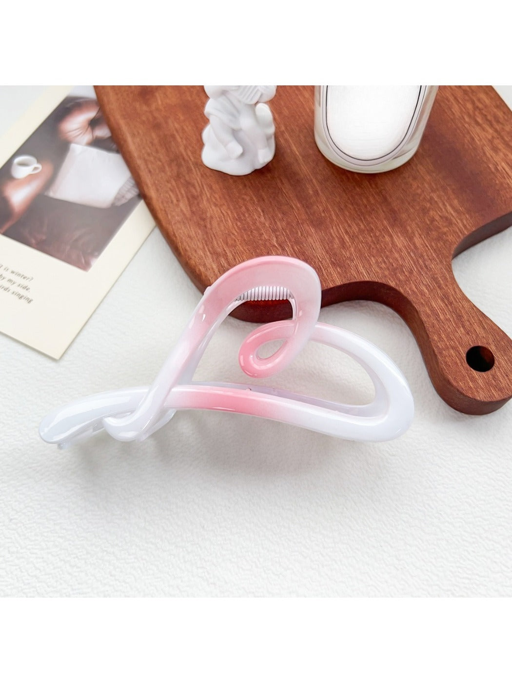 Beau heart shaped bow claw clip in ombre gradient resting on a pastel colored fabric