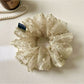 Khaki mesh scrunchie with white polka dots on a white background