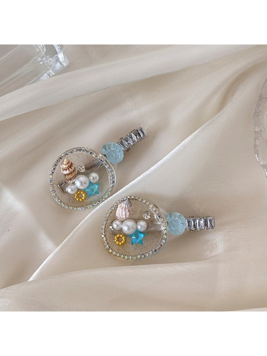 Beau hair clip featuring a large conch shell decoration on a gold-toned base