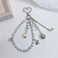 Golf ball charm keychain hanging from a set of keys on wooden surface