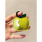 Red apple keychain with silver ring placed on a textured fabric surface