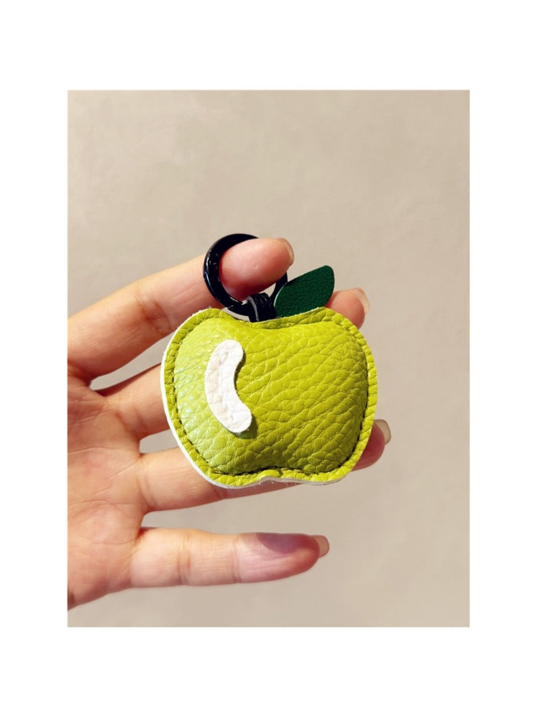 Red apple keychain with silver ring placed on a textured fabric surface