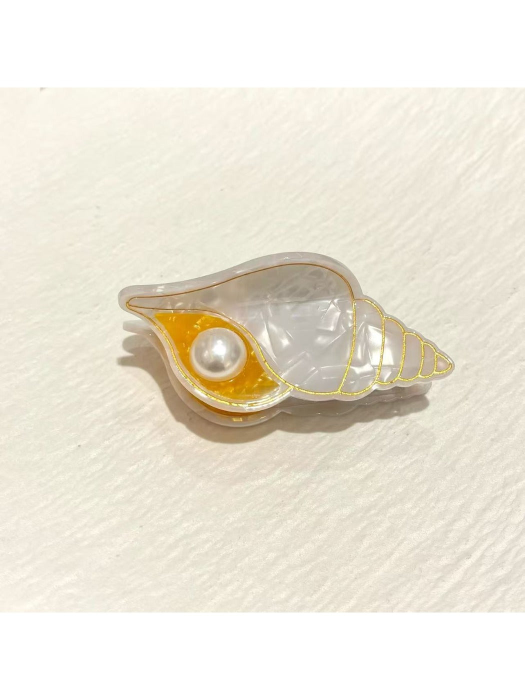 Beau starfish and conch claw clip held in hand showing size and scale