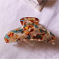Beau chic tiny floral acetate claw clip resting on fabric background