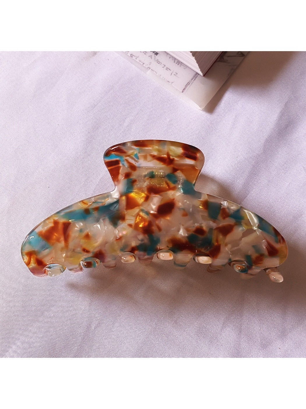 Beau chic tiny floral acetate claw clip resting on fabric background