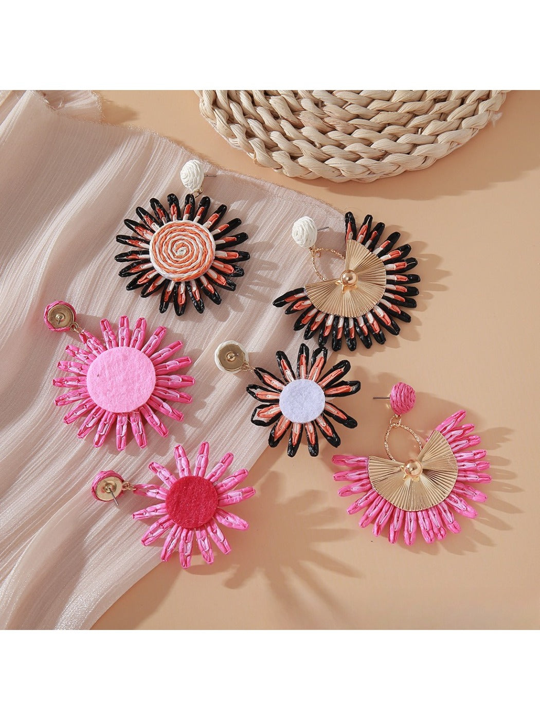 Pair of pink and black raffia woven earrings displayed on white background