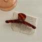 Beau chic acetate claw clip photographed with soft shadows on a neutral background