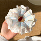 Blue plaid scrunchie with delicate white lace trim on a white background