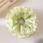 Light green fabric scrunchie with ruffle detailing on a white background