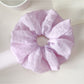 Scrunchie displayed on a white background highlighting its colorful pattern